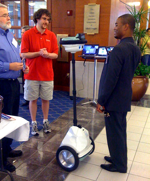 Stephen Wolfram greets a reception guest via an Anybot telepresence robot